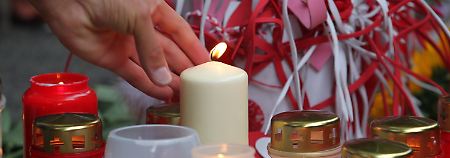 Tausende Menschen kommen zum Unglücksort und legen Blumen nieder, zünden Kerzen an.