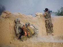 Ein afghanischer Soldat schießt mit einem Raketenwerfer. Links Kollegen der US-Armee.