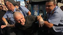 Sicherheitskräfte nehmen einen Demonstranten fest.