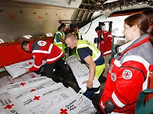 Mitarbeiter des Deutschen Roten Kreuzes und des Flughafens verstauen auf dem Berliner Flughafen Schönefeld Hilfsgüter in eine Antonov An-12.