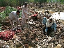 Pakistaner suchen zwischen Schlamm, Dreck und Trümmern nach ihren Habseligkeiten.