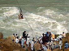 Im Swat-Tal versuchen Pakistaner über den Fluss zu kommen - das Wasser hatte die Brücke mitgerissen.