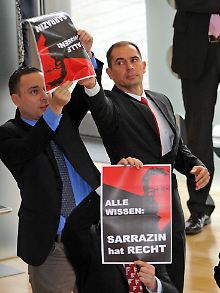 Mitarbeiter des Sächsischen Landtages entfernen im Plenarsaal während der Rede des Bundespräsidenten Plakate der NPD-Fraktion.