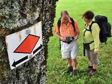 Beliebtes Hobby: Wanderer bei St. Märgen im Schwarzwald, im Vordergrund die rote Raute, Symbol für den Westweg durch den Schwarzwald.