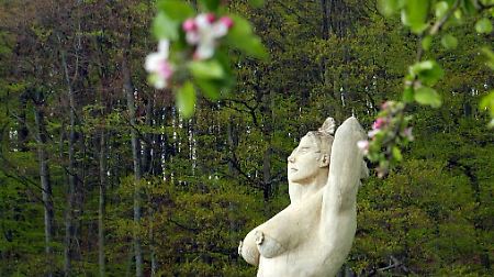 Die üppige "Deutsche Apfelkönigin" des Künstlers Peter Lenk steht auf einer Streuobstwiese und guckt sinnend in die Landschaft von Etzleswenden. 