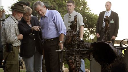 Bundeskanzlerin Angela Merkel und US-Präsident George Bush bestaunen in Trinwillershagen den  gegrillten Damhirsch.