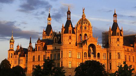 Von der Abendsonne angestrahlt steht das Schweriner Schloss während der sogenannten Blauen Stunde auf einer Insel im Burgsee.