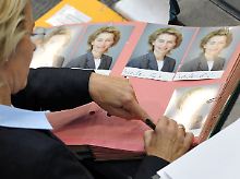 Arbeitsministerin von der Leyen unterschreibt derweil Autogrammkarten.