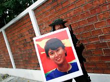 Ein Aktivist in Soldatenverkleidung mit dem Bild der unter Hausarrest gestellten Friedensnobelpreisträgerin Aung San Suu Kyi.