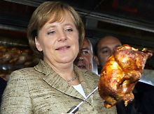 Beißt sie nun 'rein oder nicht? So ganz überzeugt scheint Kanzlerin Merkel nicht zu sein.