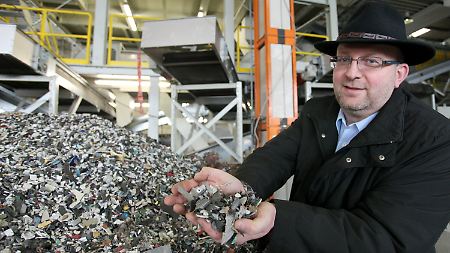 Adamec hält zerkleinerten Elektronikschrott in den Händen, der anschließend in alle einzelnen Rohstoffe getrennt wird.