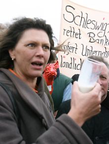 Mit einem Glas frischer Milch in der Hand steht Bundeslandwirtschaftsministerin Ilse Aigner am 08. Mai 2009 vor demonstrierenden Milchbauern auf der schleswig-holsteinischen Halbinsel Nordstrand.
