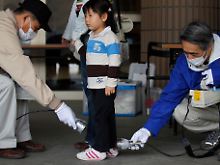 Vor einem Evakuierungszentrum in Fukushima wird eine Dreijährige auf Strahlung untersucht.