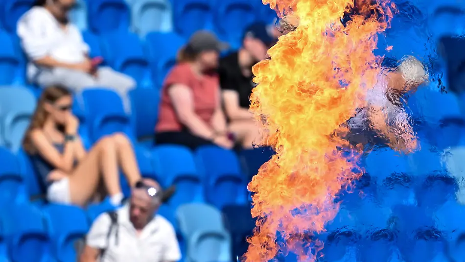 11-08-2026-Grossbritannien-Birmingham-Leichtathletik-Europameisterschaft-Zuschauer-verfolgen-die-Wettkaempfe-auf-der-Tribuene-Im-Vordergrund-sind-Flammen-von-einer-Pyro-Show-im-Stadion-zu-sehen