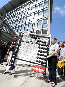 Stuttgart-21-Gegner demonstrieren vor einem Bahn-Gebäude in Stuttgart mit einem Rechenschieber gegen den Tiefbau.