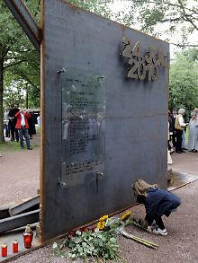Ein kleines Mädchen legt am gerade eingeweihten Denkmal Blumen nieder.