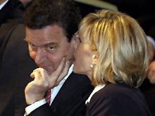 Der ehemalige Bundeskanzler Gerhard Schröder konzentriert sich ganz auf das, was ihm seine Frau ins Ohr flüstert.