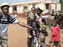Touristen mit Rad in Soweto: von den Kindern neugierig bestaunt.