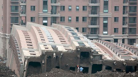 In einem Stück: Hochhaus in Shanghai kippt um