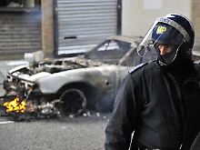 Ein Polizist vor einem noch kohlenden Auto in Hackney.