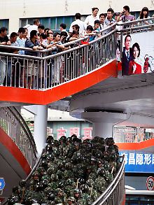 Han-Chinesen beobachten auf einer Brücke den Aufmarsch der Soldaten.