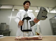 Die Angst isst mit: Ein Mitarbeiter der Gesundheitsbehörde überprüft Fleisch auf Kontamination.
