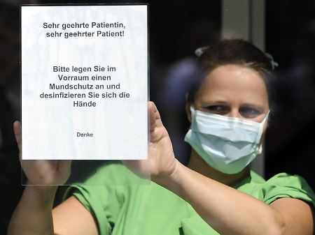 Schwester Kristina befestigt in Hamburg am Eingang zur neuen UKE-Ambulanz für Schweinegrippe-Verdachtsfälle ein Schild, das Patienten zum Tragen eines Mundschutzes und zum Hände desinfizieren auffordert.