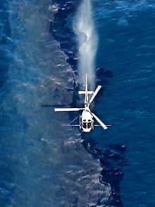 Ein Hubschrauber verteilt Chemikalien auf dem Ölteppich.