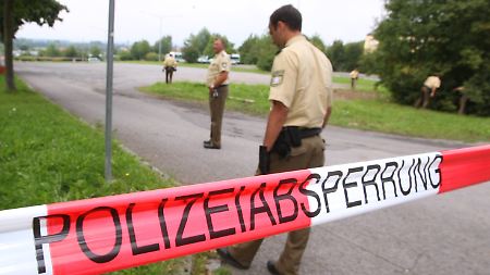 Polizeibeamte suchen am Rande des Parklplatzes nahe dem Eisstadion in Schweinfurt (Unterfranken) nach Spuren.
