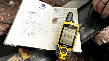 Behältnis von Geocachern mit Logbuch und Kleinigkeiten zum Tauschen in einem Versteck vor dem Eingang eines Bunkers.