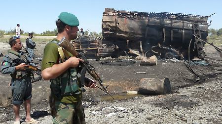 Afghanische Sicherheitskräfte sichern den Ort des Angriff, im Hintergrund ein zerstörter Tanklaster.