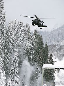 Ein Hubschrauber der österreichischen Armee befreit Bäume von Schnee.