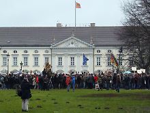 Irritierte Bürger vor dem Schloss Bellevue zeigen Wulff den Schuh.