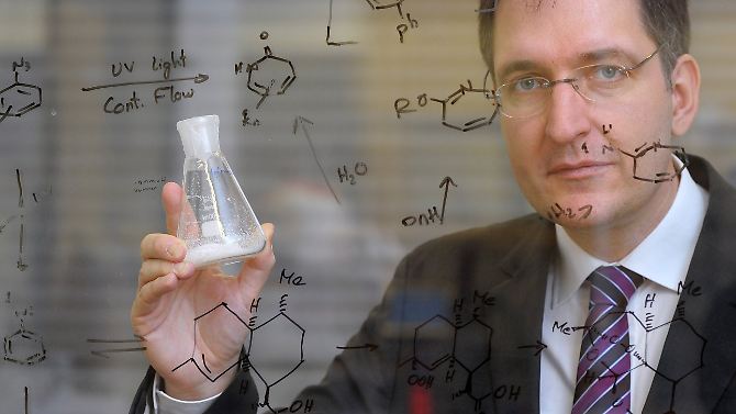 Peter H. Seeberger, Direktor am Max-Planck-Institut, zeigt in einem Labor hinter einer Glasscheibe, auf der unter anderem die Formel zur Synthese des Wirkstoffes Artemisinin aufgeschrieben ist, eine Probe des Stoffes.
