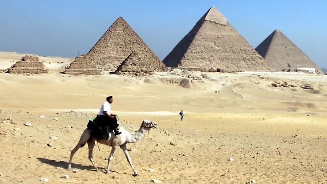 Ein ägyptischer Polizist auf einem Kamel geht vor den Pyramiden von Gizeh auf Streife.