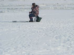 Ein Eisangler sitzt im Hafen von Stralsund.