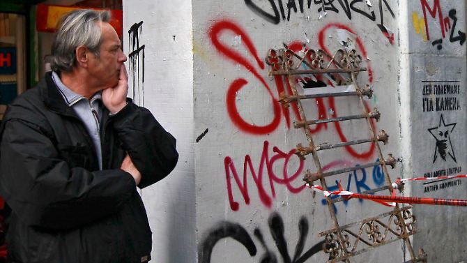 Ein Athener Ladenbesitzer schaut sich die Zerstörungen der Nacht an. Wie geht es weiter in Griechenland?