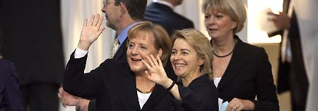 Kanzlerin Merkel und Familienministerin von der Leyen winken zur Besuchertribüne, wo von der Leyens Mann mit vier der sieben Kinder sitzt.