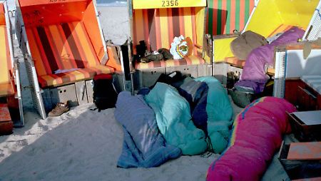 Jugendliche übernachten in Schlafsäcken am Südstrand von Westerland.
