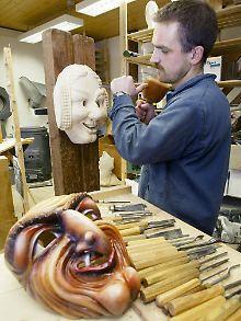 Unter dem Schnitzmesser verwandelt sich ein grober Holzblock bald in eine kunstvolle Fratze.