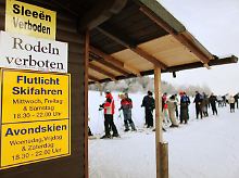 Hinweisschilder in zweisprachiger Ausführung an einer Skilifthütte.