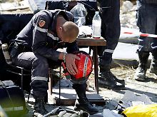 Rettungsteams, hier erschöpfte französische Helfer, kommen nur langsam in das zerstörte Land.
