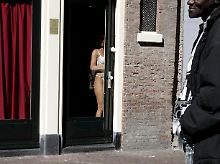 Eine Amsterdamer Prostituierte wartet an der Tür ihres Appartements im Amsterdamer Rotlichtviertel auf Kunden.