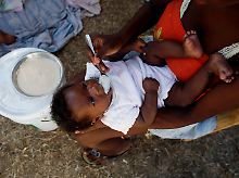 In einer Zeltstadt in Port-au-Prince füttert eine Mutter ihr Kind.