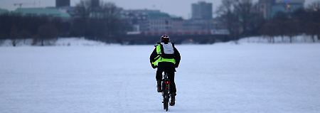 Ein Radfahrer fährt über die zugefrorene Außenalster.