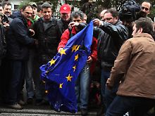 In Athen versuchen Griechen, eine EU-Flagge zu verbrennen.