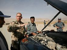 Ein Soldat der Bundeswehr erklärt afghanischen Polizisten, wie ein Fahrzeug durchsucht wird. 