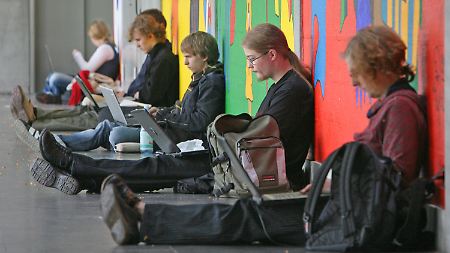 Studenten sitzen vor einem Hörsaal der TU Dresden auf dem Boden.