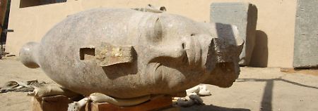 Der Kopf gehört zu einer Figur, die den Pharao sitzend mit vor der Brust verschränkten Armen zeigt. 