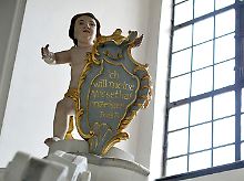 Eine Kindsfigur über einem Beichtstuhl in der Basilika Vierzehnheiligen in Bad Staffelstein (Oberfranken) hält eine Tafel mit einem Buß-Psalm.